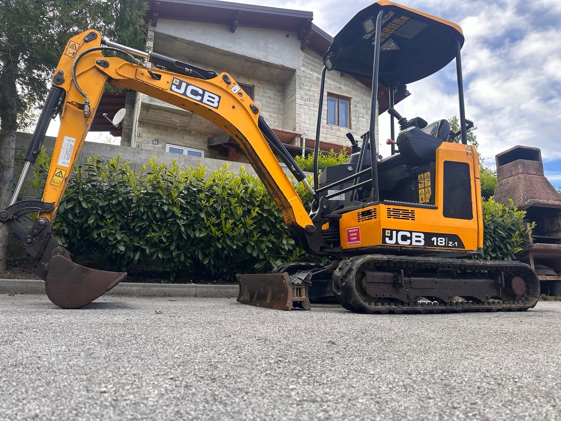 Žuti JCB mini bager snimljen s bočne strane